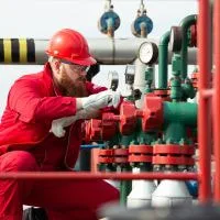 Oil and gas field technician inspecting valve during operations 