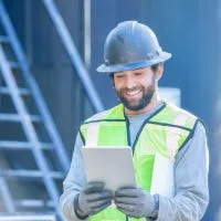 Oil and gas worker using a tablet to monitor safety and compliance data in real-time on-site.